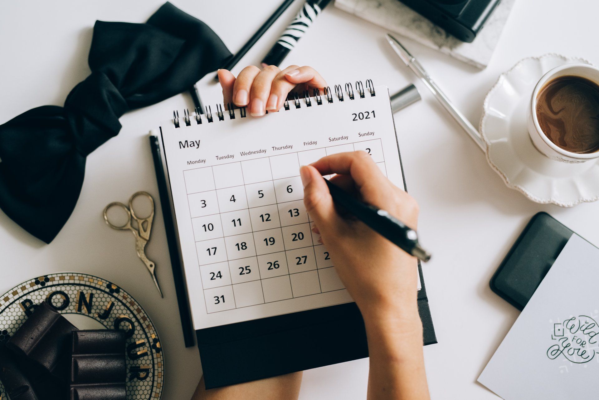 A calendar page open on a desk beside binoculars and scissors